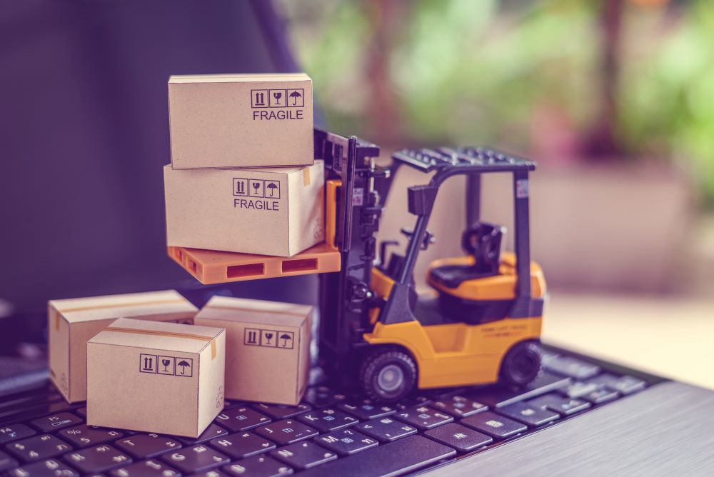 Miniature forklift carrying packages across laptop keyboard